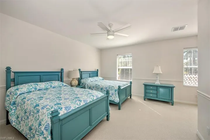 Neutral wall paint, ceiling fan with integrated lighting, two windows with blinds, and light-colored carpeting