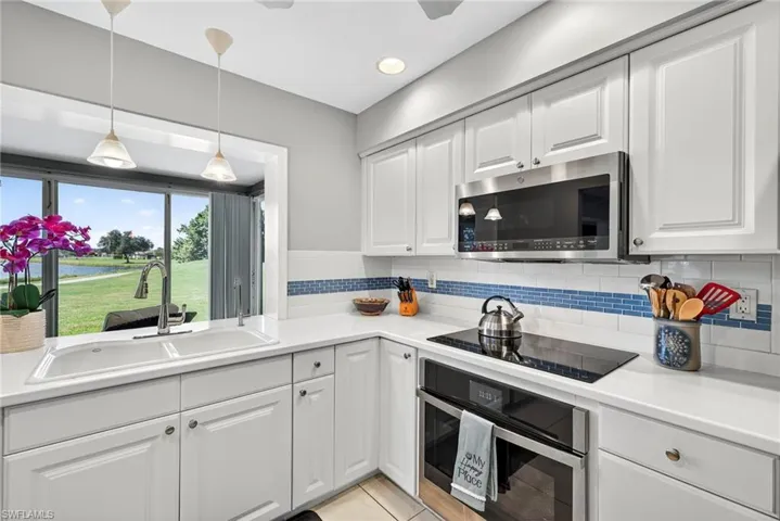 Kitchen featuring appliances with stainless steel finishes, white cabinets, tasteful backsplash, light tile patterned flooring, and recessed lighting