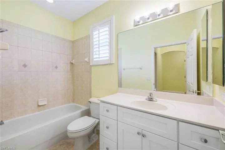 Full bathroom with vanity with extensive cabinet space, tile flooring, toilet, and tiled shower / bath combo