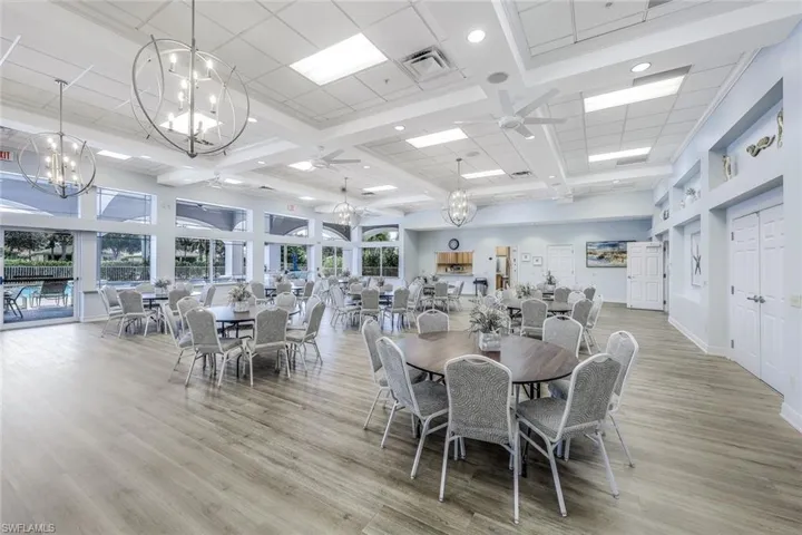 Dining space featuring beam ceiling, a high ceiling, light wood-type flooring, and ceiling fan with notable chandelier