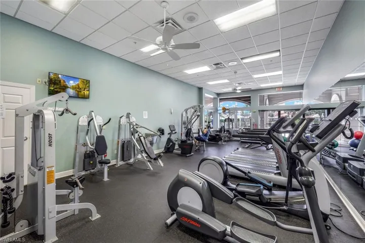 Exercise room featuring ceiling fan and a drop ceiling