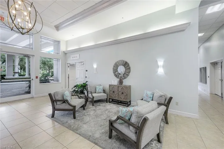 Tiled living room featuring a high ceiling, a raised ceiling, and a chandelier