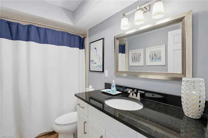 2nd bathroom featuring curtained shower/tub and granite vanity