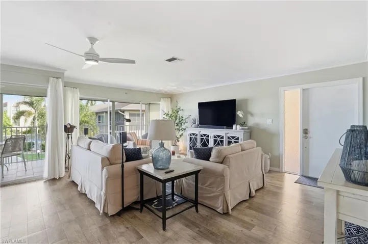 Living room with light wood-style floors, ornamental molding, and a ceiling fan