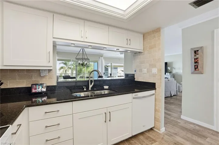 Shaker white cabinets, granite countertops, dishwasher, and crown molding