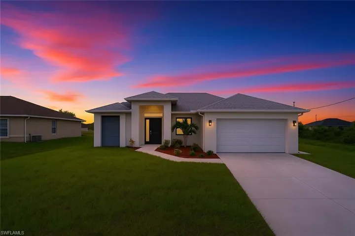 Prairie-style home with a garage, driveway, a yard, and stucco siding