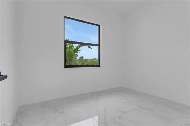 Spare room featuring marble look tiles and baseboards