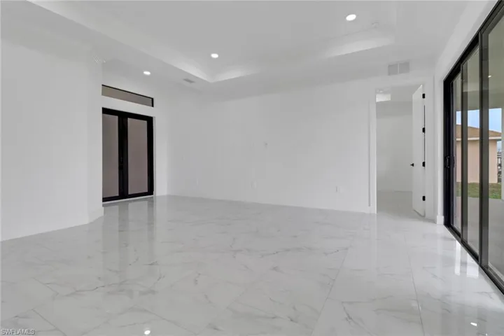 Unfurnished room with a raised ceiling, recessed lighting, marble finish floors, and crown molding