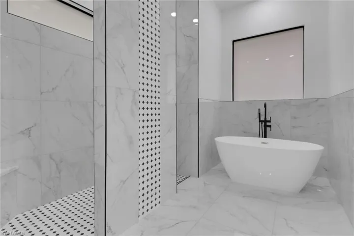 Full bathroom with a marble finish shower, a freestanding tub, marble tiled floors, and tile walls