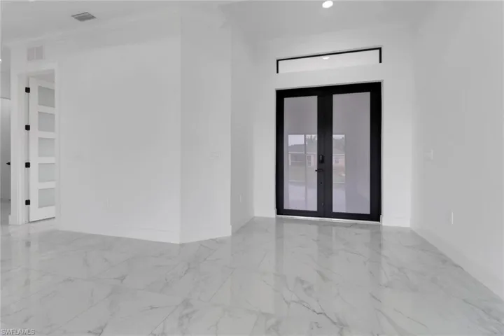 Empty room featuring french doors, marble finish floors, baseboards, and crown molding