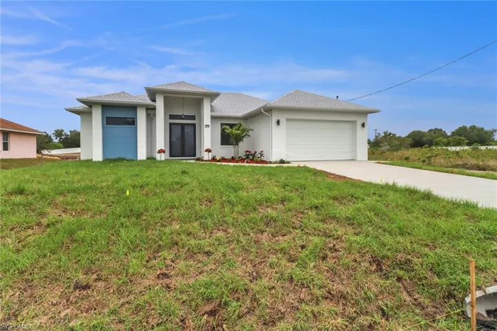Prairie-style house featuring an attached garage, stucco siding, a front lawn, and driveway