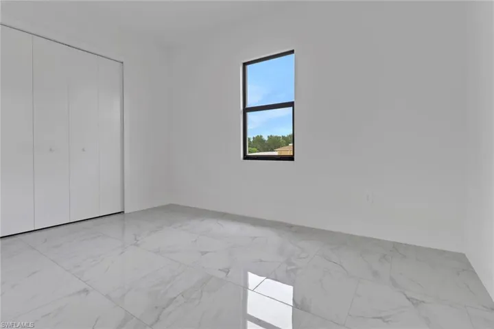 Unfurnished bedroom featuring light marble finish floors and a closet