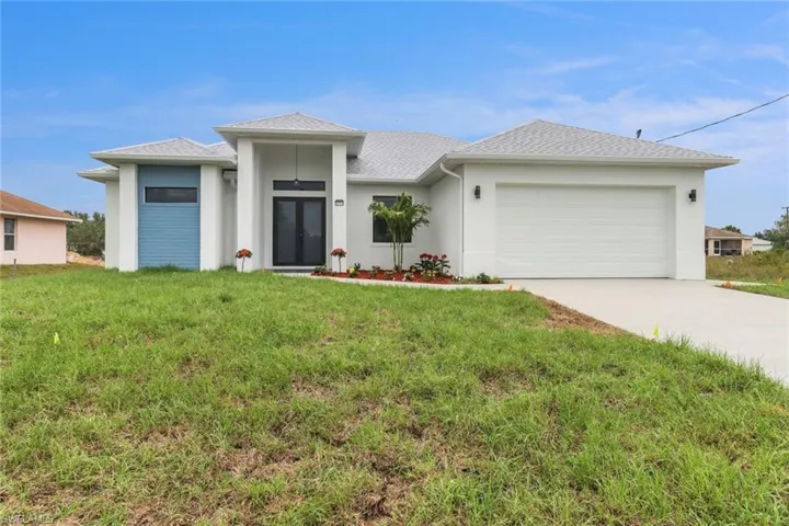 Prairie-style home with a front yard, concrete driveway, an attached garage, and stucco siding