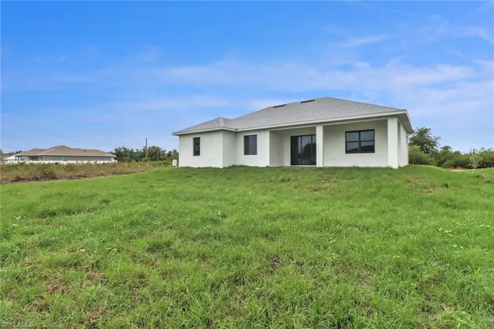 Back of property featuring a yard and stucco siding