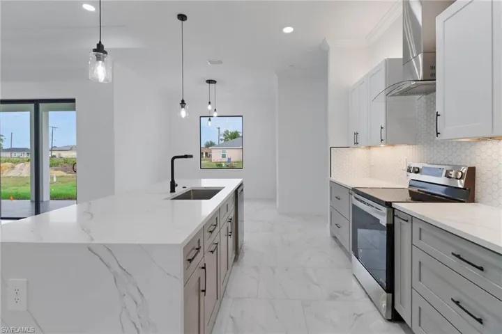 Kitchen with stainless steel range with electric stovetop, a sink, wall chimney range hood, decorative backsplash, and recessed lighting