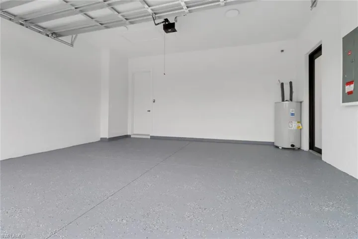 Garage featuring water heater, a garage door opener, and electric panel