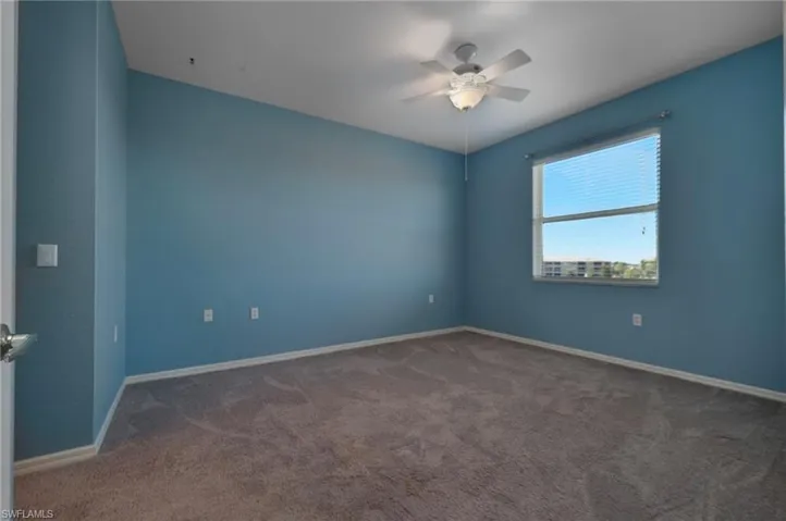 Unfurnished room featuring dark colored carpet and ceiling fan