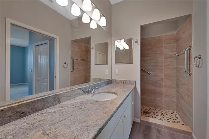 Bathroom featuring vanity, a shower stall, and dark wood-style flooring