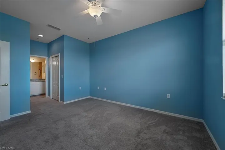 Unfurnished bedroom with dark carpet, a closet, and a ceiling fan