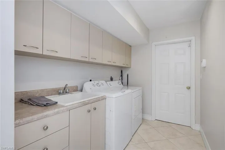 Laundry area with cabinet space, light tile patterned floors, and separate washer and dryer
