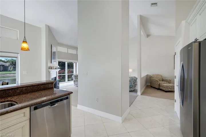 Kitchen with stainless steel appliances, dark stone counters, a high ceiling, decorative light fixtures, and open floor plan