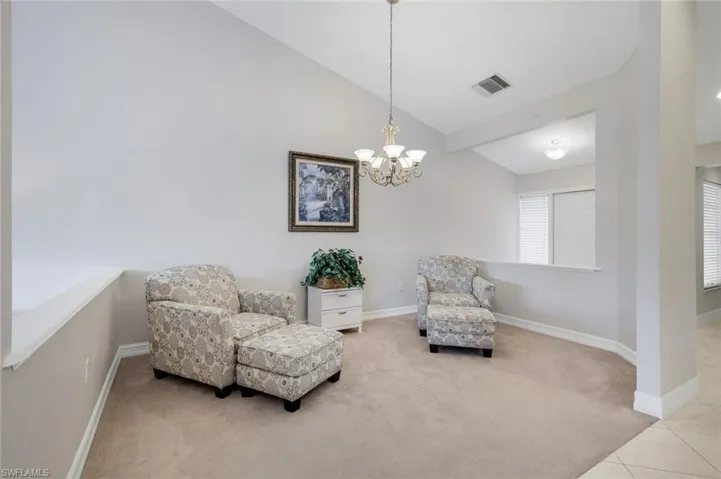 Living area with carpet flooring, vaulted ceiling, and a chandelier