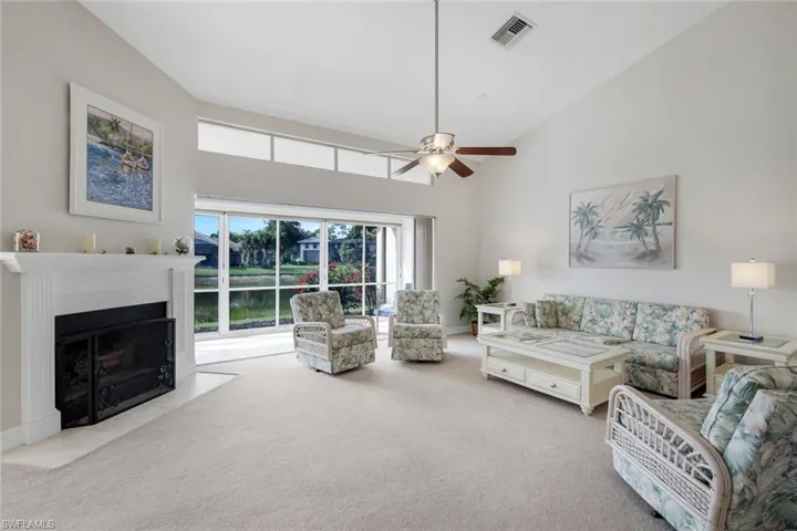 Living room featuring light carpet, ceiling fan, lofted ceiling, and a fireplace with flush hearth
