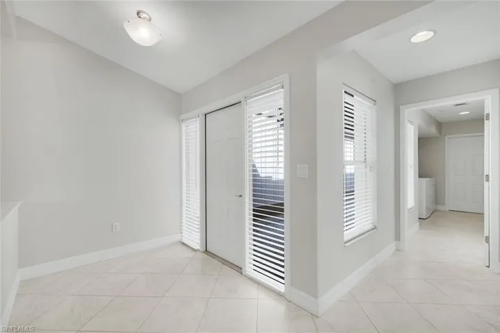Foyer entrance featuring light tile patterned floors and vaulted ceiling