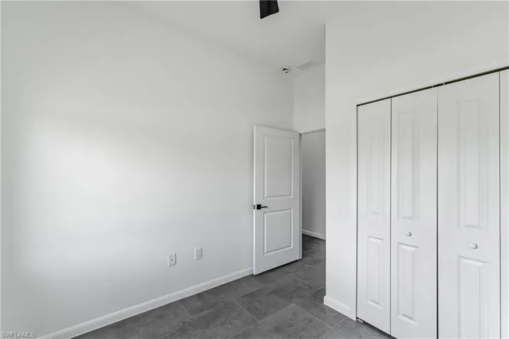 Interior room featuring neutral wall paint, grey tile flooring, and white bi-fold closet doors