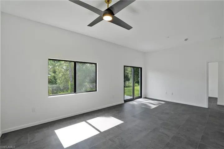 Spacious room featuring neutral walls, dark tile flooring, a modern ceiling fan, and recessed lighting
