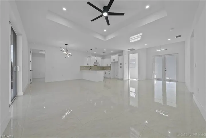 Unfurnished living room with french doors, ceiling fan, recessed lighting, and a raised ceiling