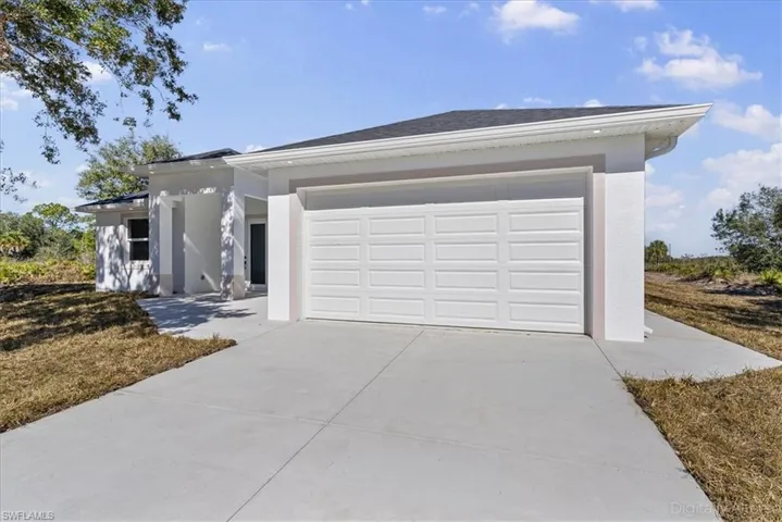 Prairie-style house with driveway, stucco siding, an attached garage, and roof with shingles