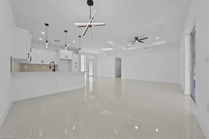 Unfurnished living room with ceiling fan, a tray ceiling, and recessed lighting