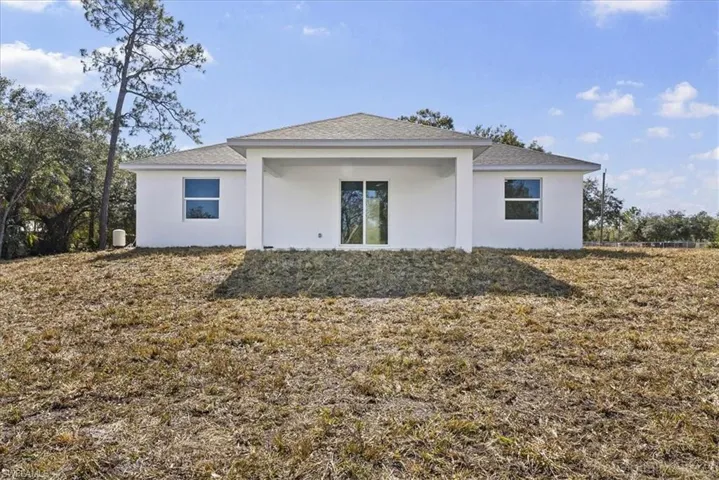 Back of property featuring stucco siding, a patio area, a yard, and a shingled roof