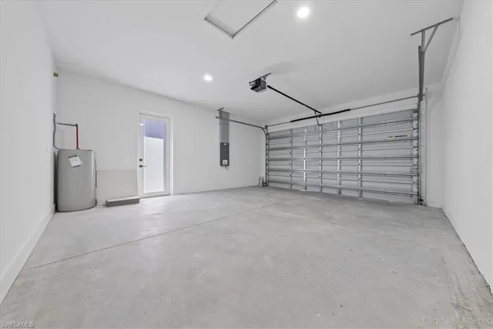 Garage featuring water heater, recessed lighting, and electric panel