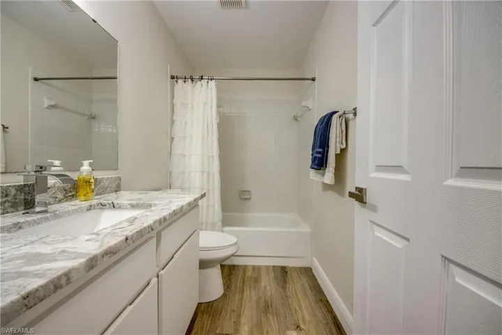 Full bathroom featuring wood finished floors, toilet, shower / tub combo, and vanity