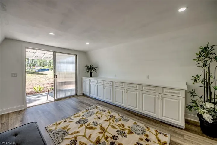 Living area featuring lofted ceiling, light wood-style flooring, baseboards, and recessed lighting