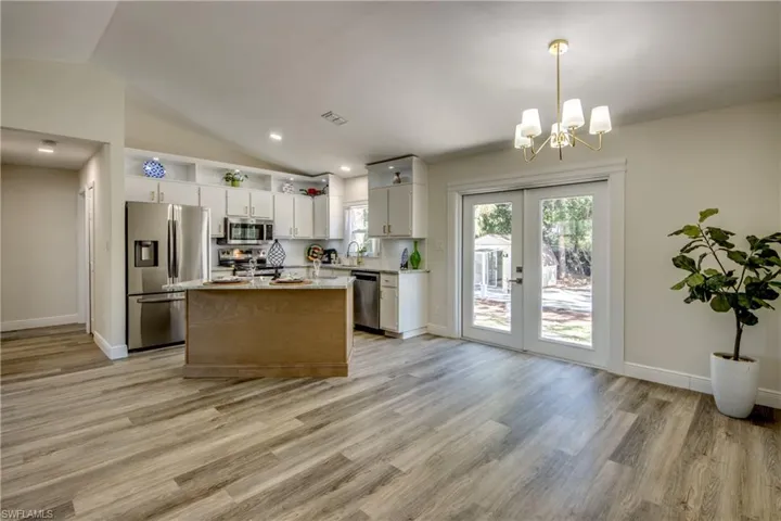 Kitchen featuring appliances with stainless steel finishes, light countertops, a chandelier, light wood-style floors, and lofted ceiling