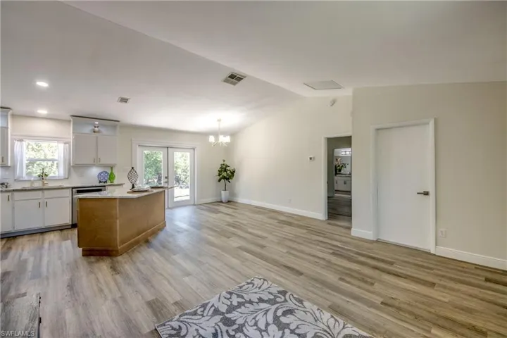 Kitchen featuring dishwasher, light countertops, light wood finished floors, a chandelier, and vaulted ceiling
