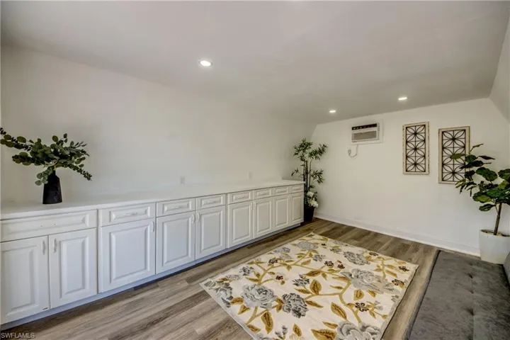 Living area featuring light wood-style floors, recessed lighting, a wall mounted air conditioner, and baseboards