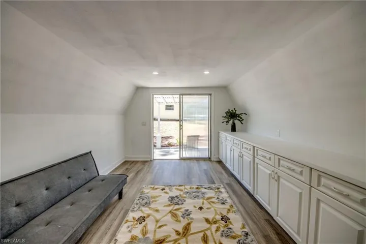 Unfurnished room featuring vaulted ceiling, wood finished floors, baseboards, and recessed lighting