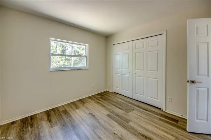 Unfurnished bedroom featuring light wood-style floors, baseboards, and a closet