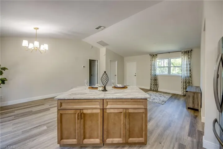 Kitchen featuring a chandelier, light wood-style flooring, baseboards, vaulted ceiling, and hanging light fixtures