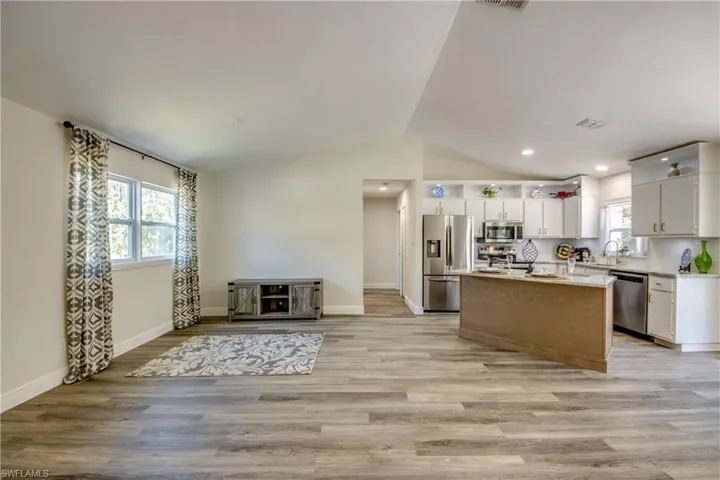 Kitchen featuring appliances with stainless steel finishes, vaulted ceiling, plenty of natural light, light wood finished floors, and a center island