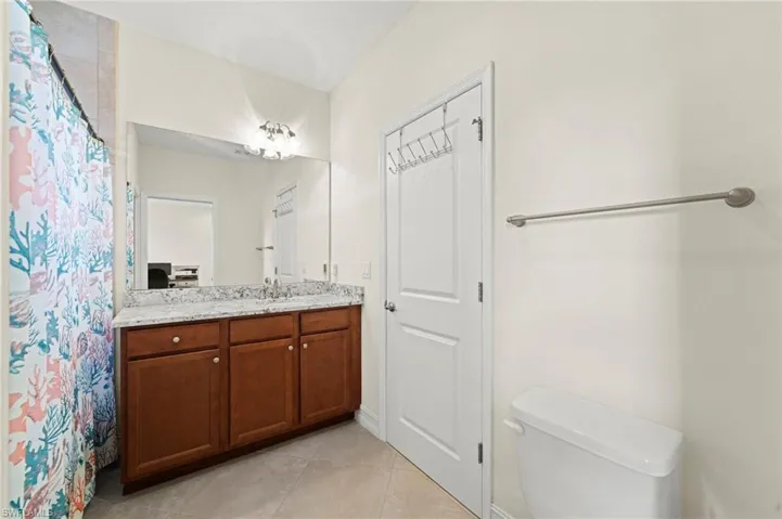 Bathroom with toilet, curtained shower, vanity, and tile patterned floors