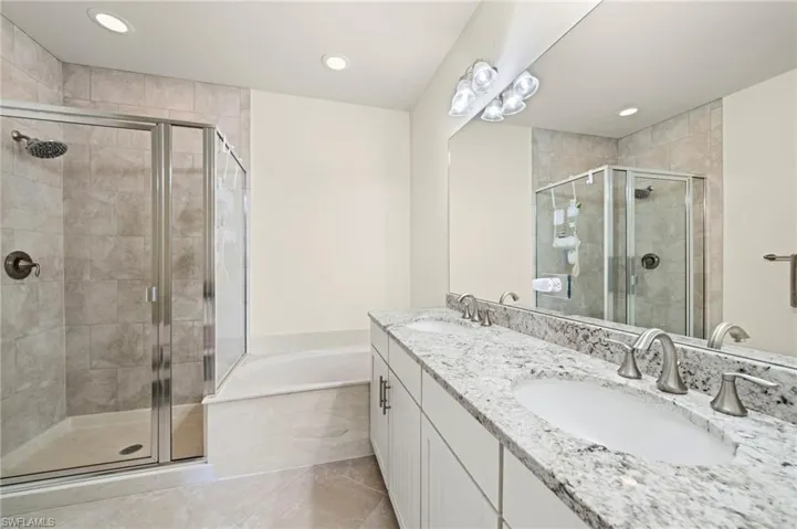 Full bathroom with a stall shower, a garden tub, and a sink