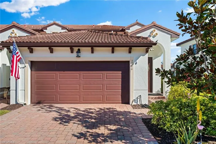 Mediterranean / spanish home with a garage, a tiled roof, decorative driveway, and stucco siding