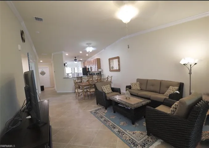 Living area featuring crown molding, light tile patterned flooring, and lofted ceiling