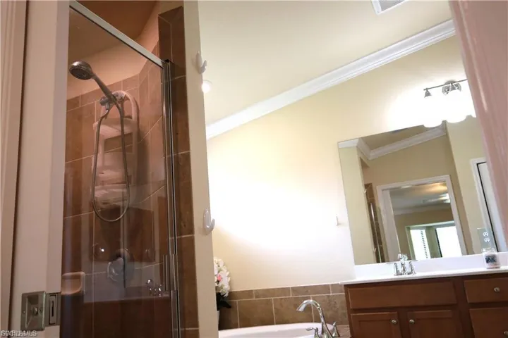 Full bath with ornamental molding, a stall shower, vanity, and a garden tub