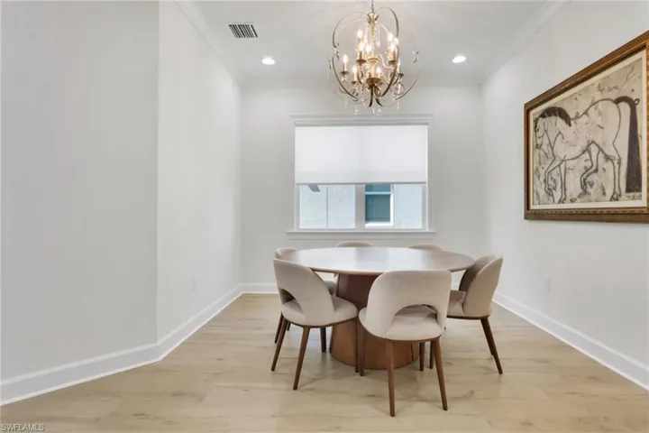 Dining space featuring light wood finished floors, crown molding, a chandelier, and recessed lighting
